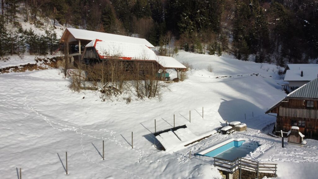 Snow-covered pool and houses at Forest Farmstay